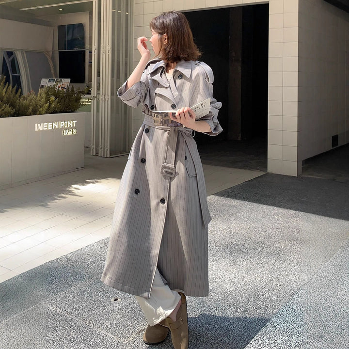 Dam lång-skärning pinstripe trenchcoat med voluminous ärmar, shoulder epaulettes, och knytband